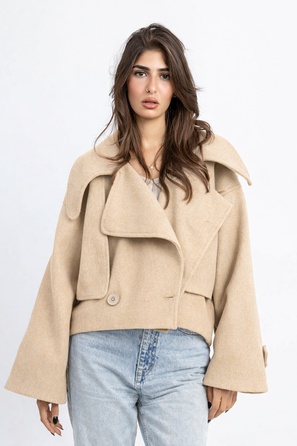 Woman wearing a beige coat and light blue jeans on a white background